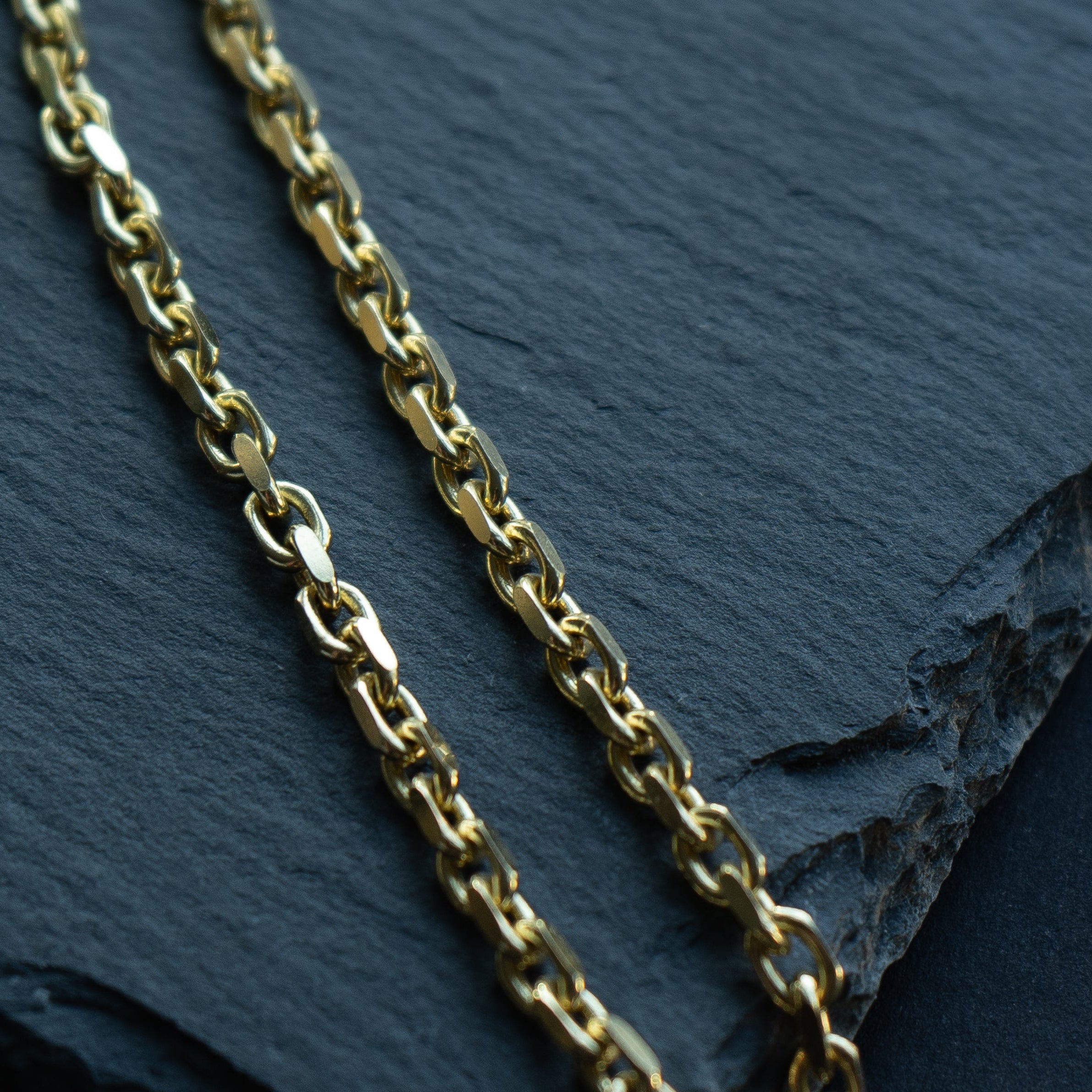 Gold chain on a dark slate surface