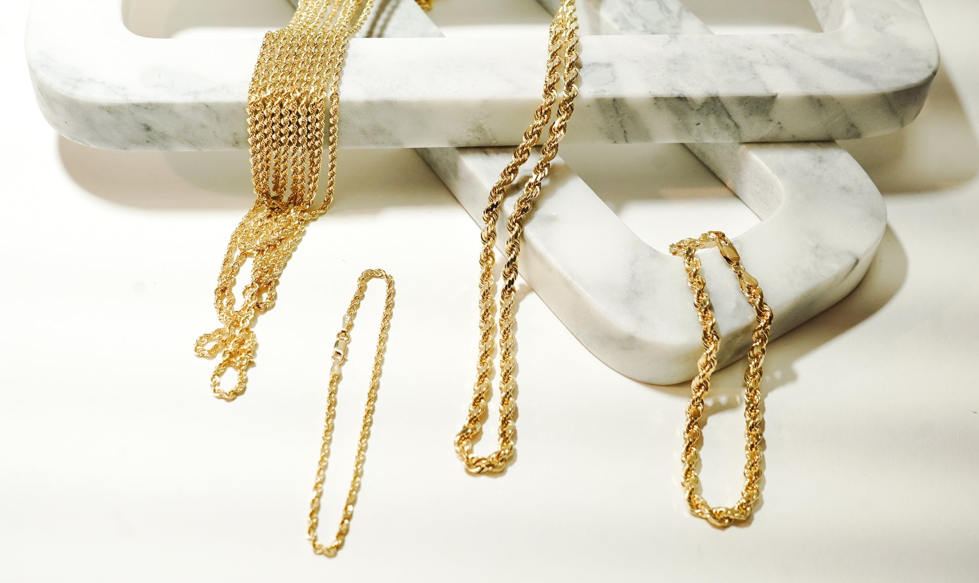 best solid gold chains for daily wear photographed on a white background using marble props